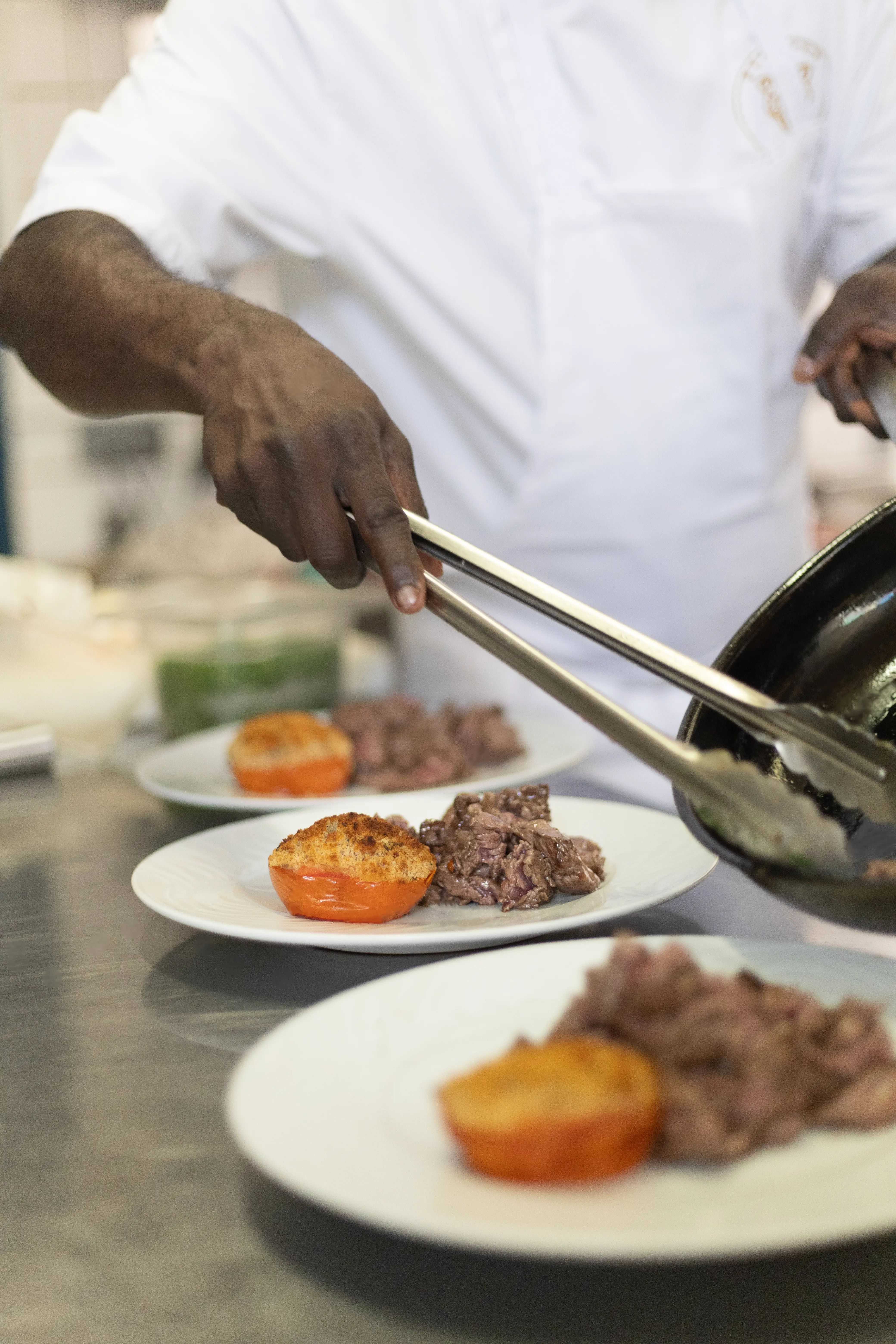 The chef plates a dish with tongs