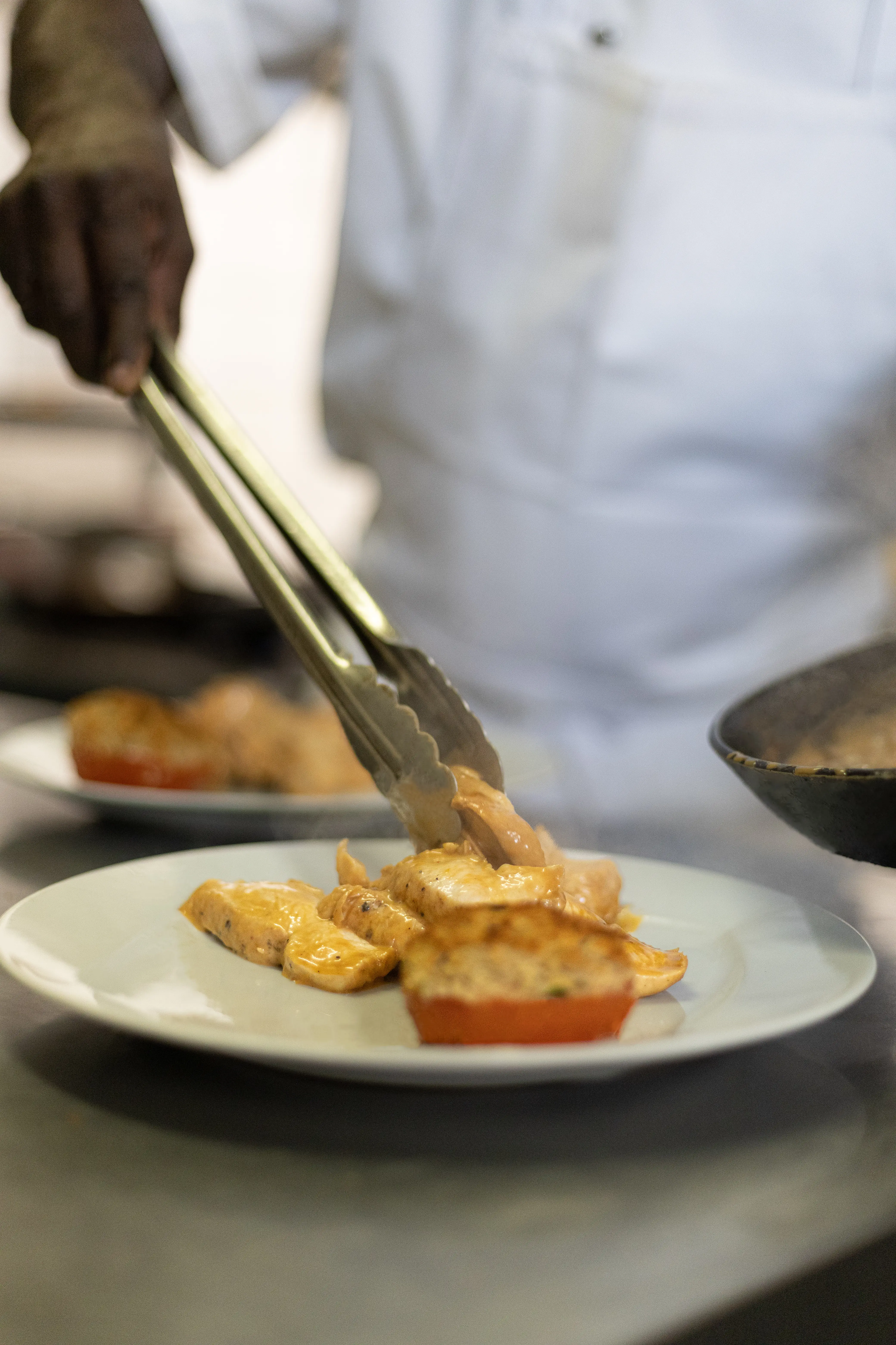 The chef arranges a plate with tongs