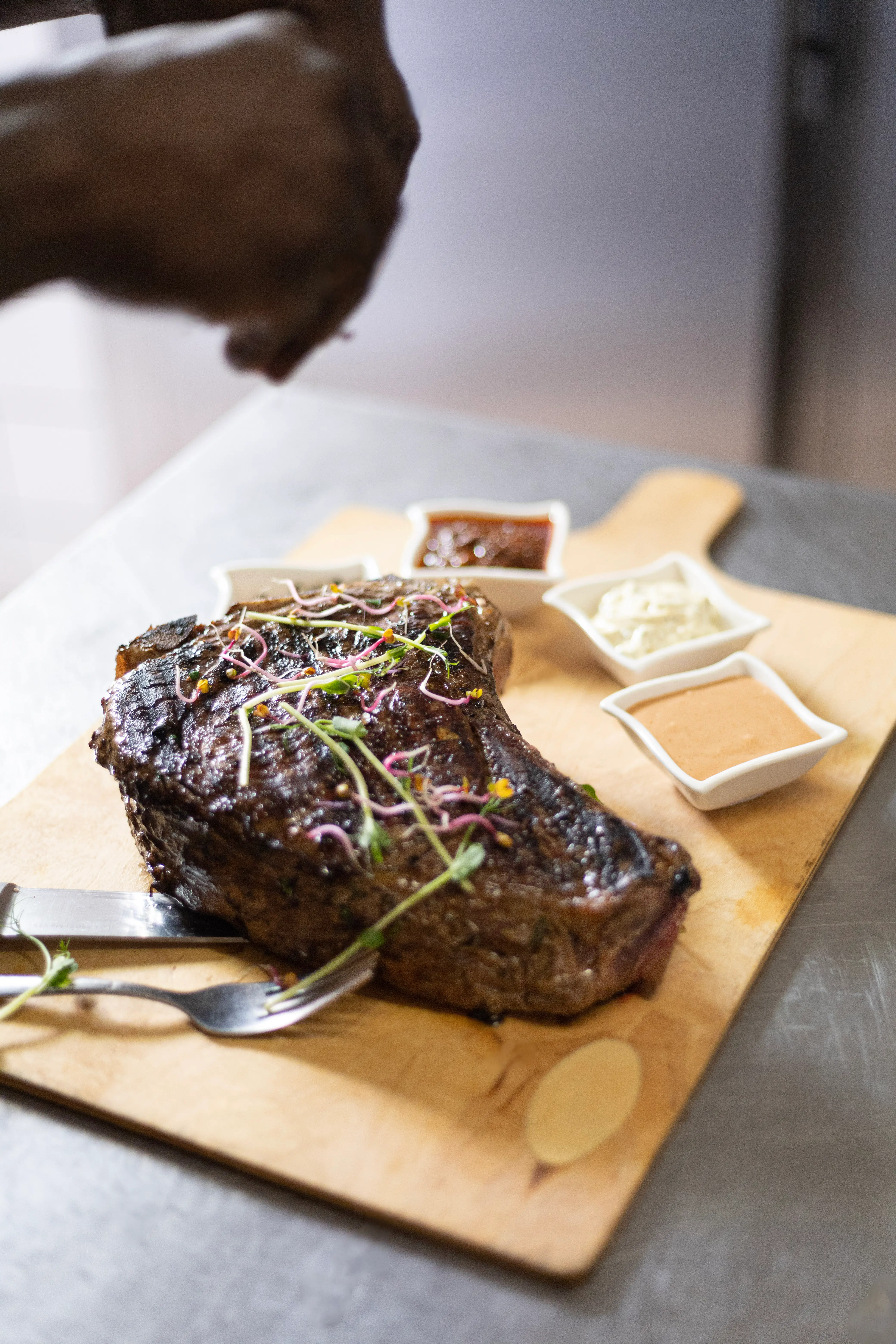 Seasoned côte de bœuf served on a board, homemade sauce